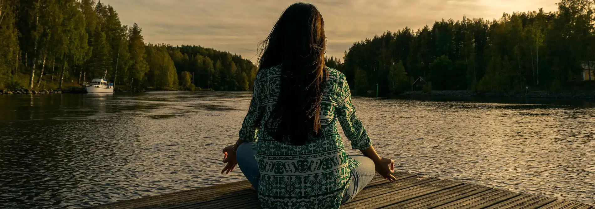 Woman sitting in yoga pose on dock