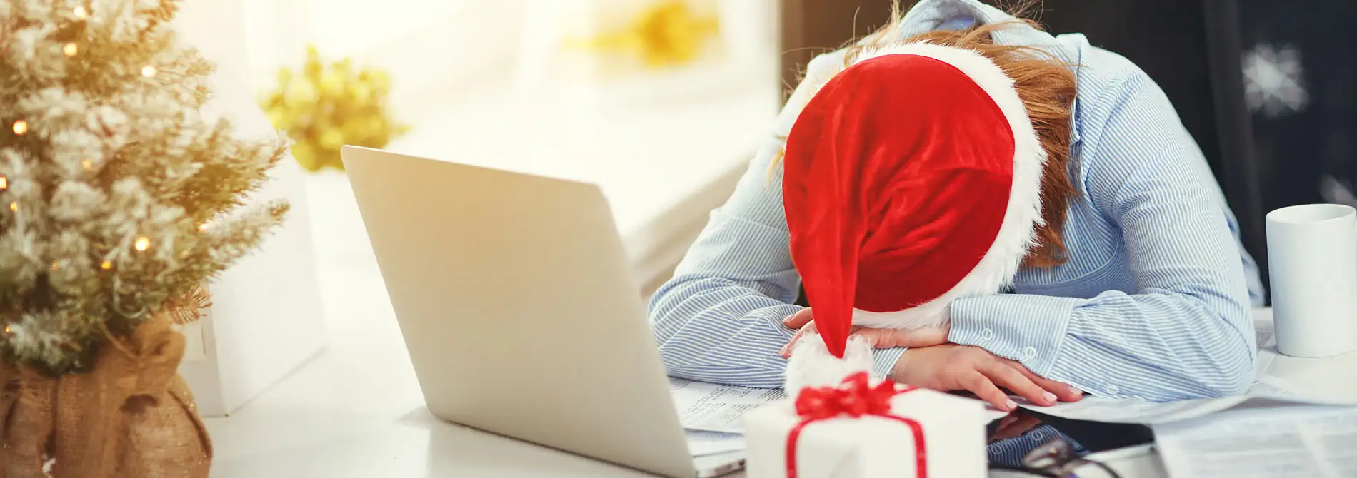 Woman sleeping at desk with santa hat on