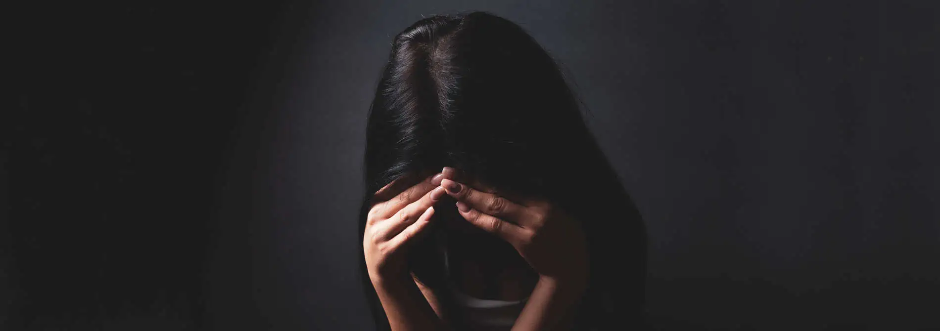 woman sad looking down holding her head with her hands
